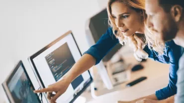 Dos personas revisando código en una computadora.