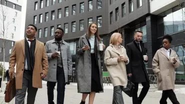 Grupo de personas caminando por la ciudad con abrigos y bebidas.