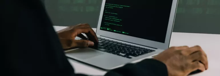 Persona escribiendo código en una laptop.