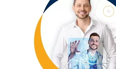 Hombre sonriente con bata médica frente a una pantalla digital.